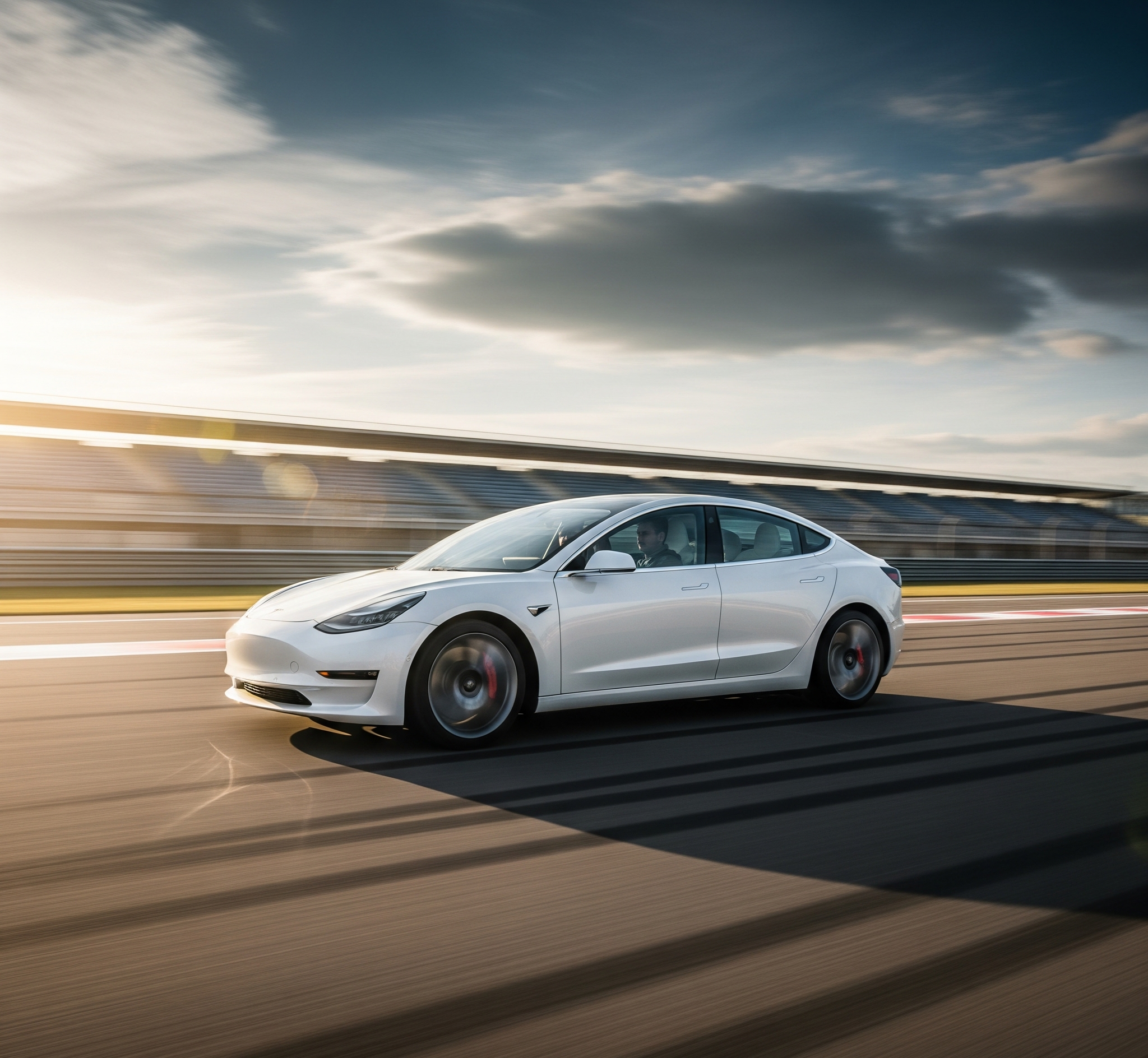White Tesla Model 3 electric sedan accelerating rapidly on a race track with motion blur.
