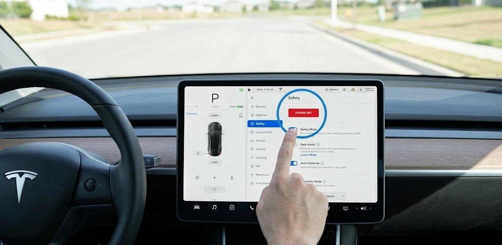 A person's hand pressing the red "Power Off" button on a Tesla Model 3 touchscreen within the Safety settings menu to manually shut down the vehicle.