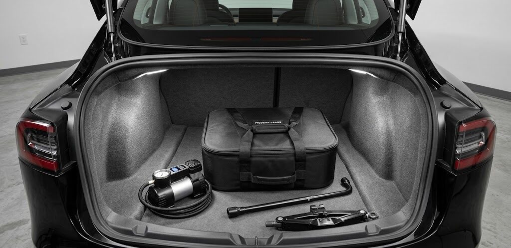 A premium aftermarket spare tire kit and jack stored neatly in the trunk of a Tesla Model 3.